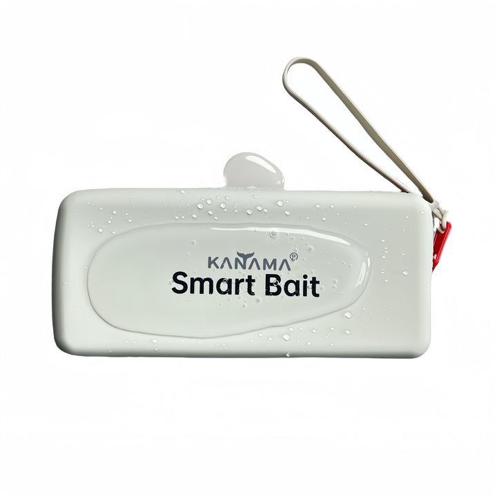 A white rectangular container with the words "Smart Bait" on it and the brand name "KANAMA" printed above. Water droplets are visible on the surface of the container, and a small amount of water has accumulated on the top. A red ring is attached to one side of the container.