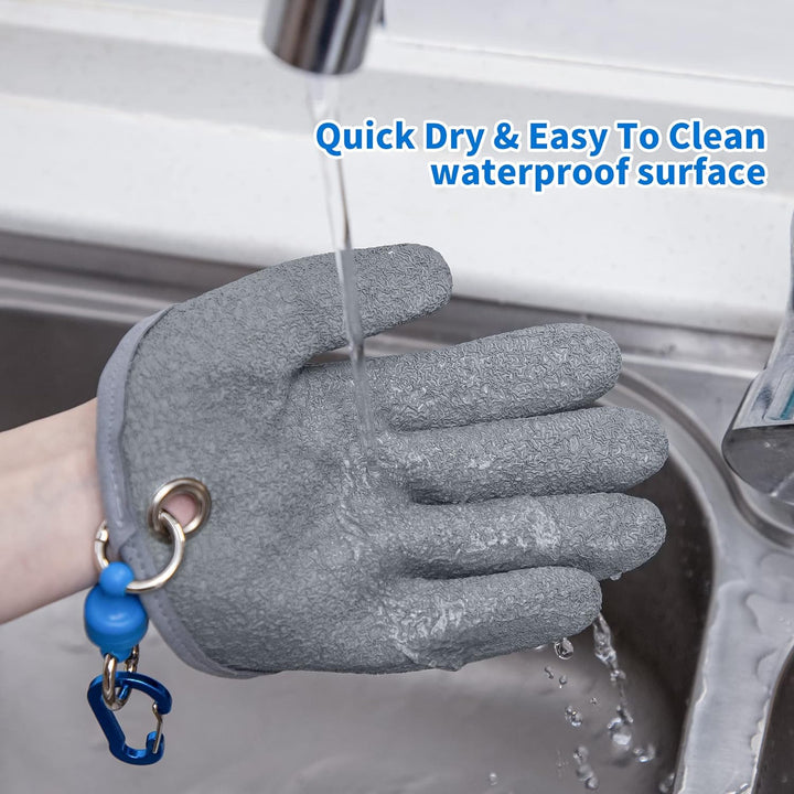 A gray waterproof glove under running water at a sink, demonstrating its easy-to-clean feature. A blue carabiner is attached to the wrist loop of the glove. The text "Quick Dry & Easy To Clean waterproof surface" is prominently displayed above the glove.